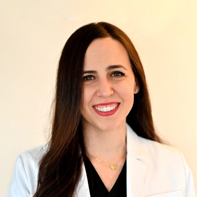 Doctor Tamara Basha smiling in front of a yellow wall.