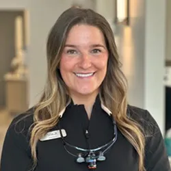 Staff with brown hair and blonde highlights smiling in a track jacket