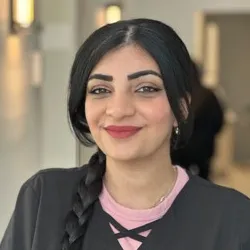 long dark haired staff wearing an over the shoulder braid with a black top layered over pink